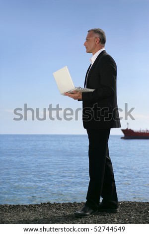 A man holding a laptop computer in front of the sea