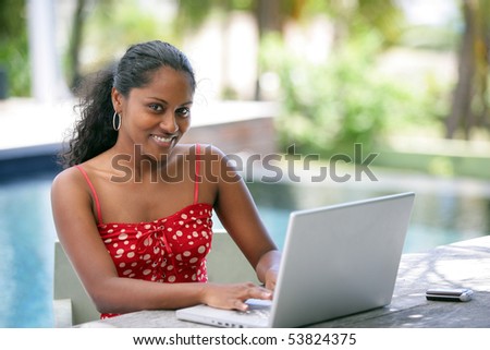 Portrait of a smiling young woman in front of a laptop computer