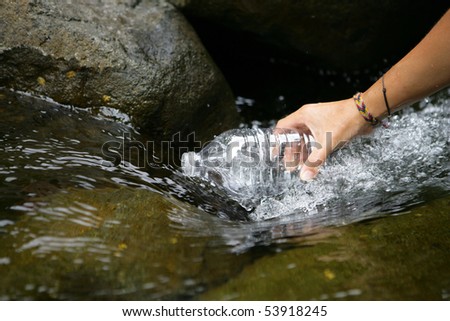 Woman filling a bottle of water in a river