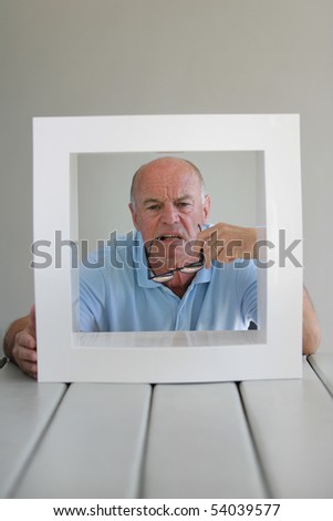Portrait of a senior man behind a white frame