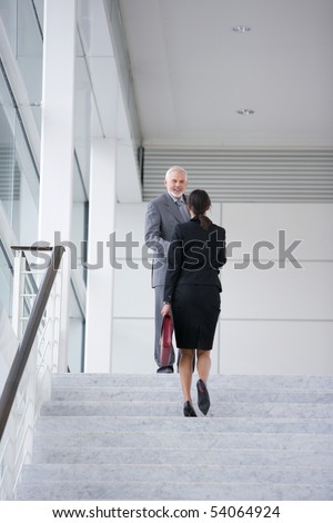 Man in suit smiling to a young woman climbing stairs