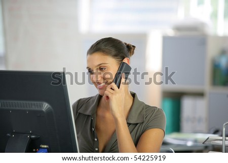 Portrait of a young woman phoning in front of a laptop computer