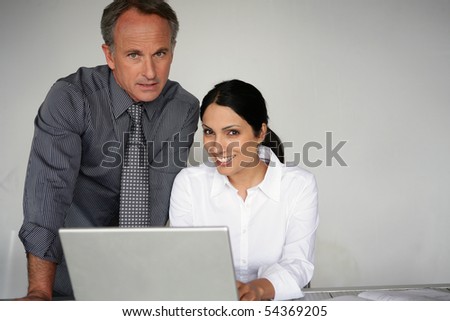 Portrait of a man in suit and a woman in front of a laptop computer