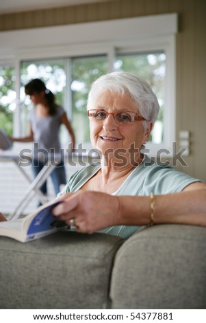 Portrait of a senior woman reading a book and a young woman ironing