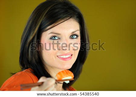 Portrait of a young woman eating sushi with chopsticks on green background