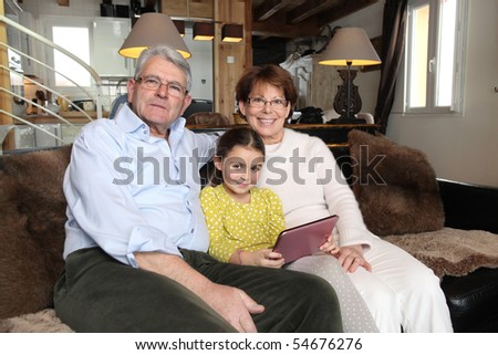 Portrait of a senior couple with a little girl in front of a portable dvd player