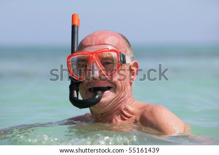 Portrait of a senior man in the sea with a snorkel and goggles