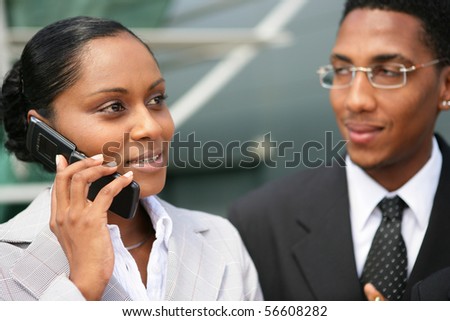 Portrait of a young woman in suit phoning near a young man in suit