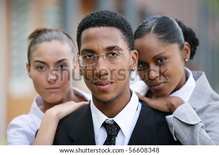 Portrait of a young man in suit standing in front of young women