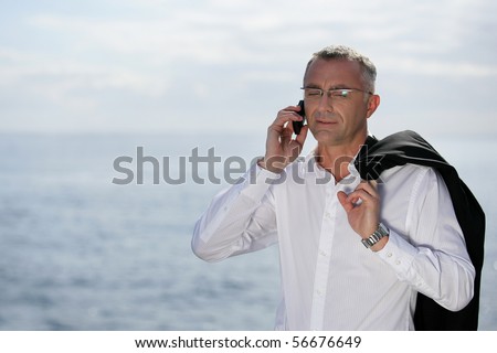 Man in suit with a mobile phone near the sea