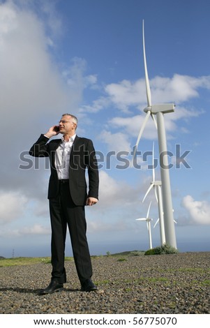 Man in suit phoning near wind turbines