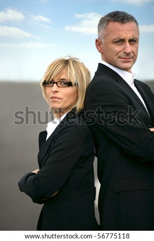 Man and woman in suit standing back to back