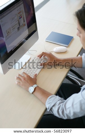 Young man in suit sitting in front of a desktop computer