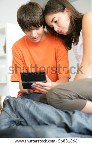 Portrait of a boy and a girl sitting on the floor with a portable game console