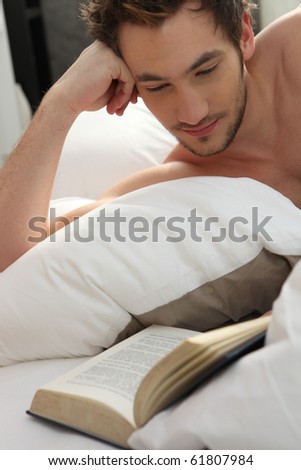 Young man reading a book in bed