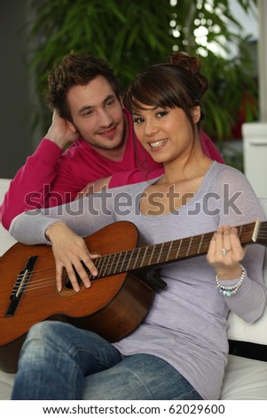 Portrait of a woman playing guitar to her friend