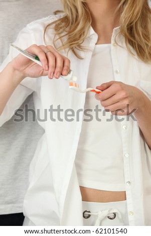 Woman spreading toothpaste on a toothbrush
