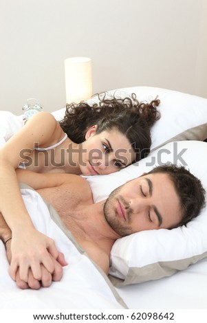 Woman lying beside a sleeping man