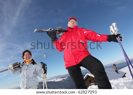 Senior man and senior woman with skis in snow