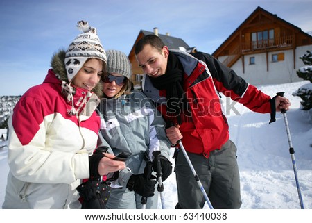 Young woman watching her mobile phone near friends in snow