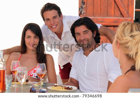 30 years old couple and a 20 years old man behind them posing outside at lunch time, summer scene