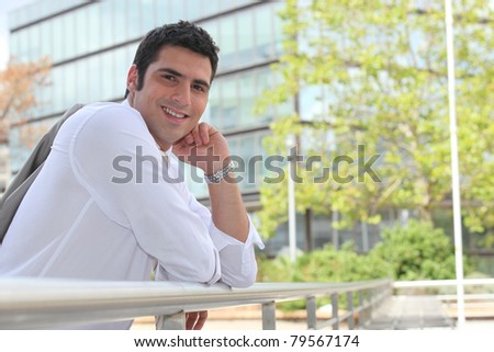 Businessman leaning on a rail in the sunshine