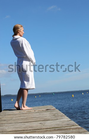 Woman in a toweling robe standing on a wooden jetty