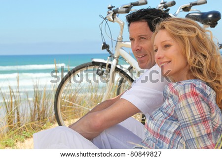 Profile picture of couple sat next to bicycles at the beach