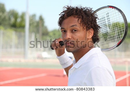 Male tennis player holding racquet over shoulder during game on hard court