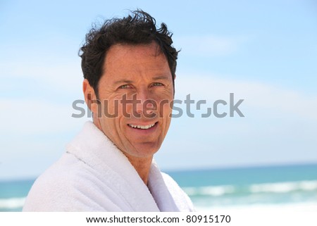 Man stood at the beach wearing bath robe