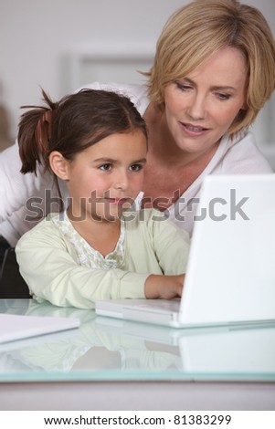 mother showing her little girl how to use the laptop