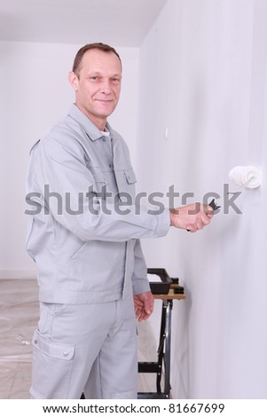 Smiling handyman painting a room white