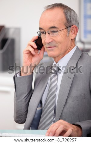 65 years old man wearing a grey suit and calling