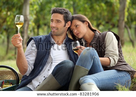 Couple sat tasting wine in vineyard