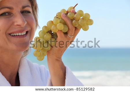 Woman eating a bunch of grapes by the sea