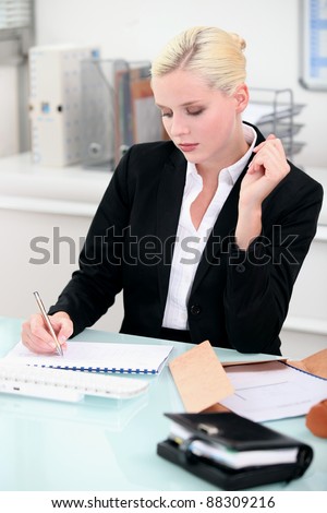 Young businesswoman writing notes at her desk