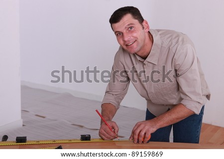 Tradesman marking a measurement on a wooden plank