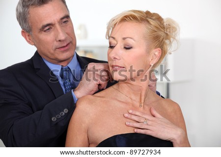 Elegant man closing the necklace of his wife