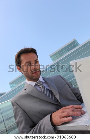 Businessman on laptop outside.