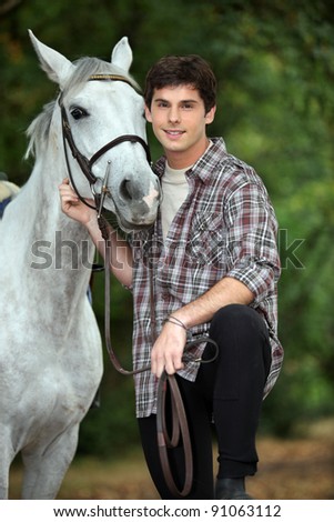 young man taking care of his horse
