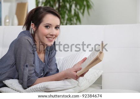 a teenage girl reading a book on a couch