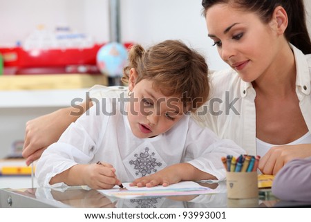 Teacher watching her pupil coloring a drawing