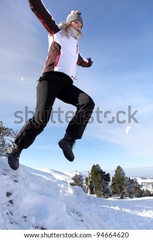 Woman jumping onto a pile of snow
