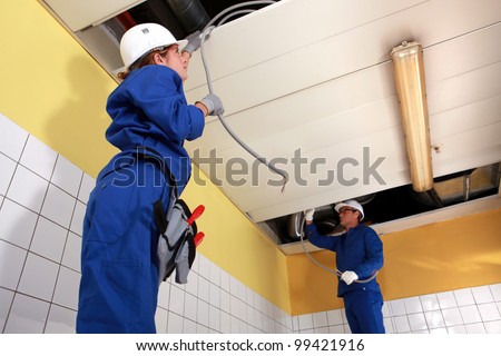 Two electrician working on ceiling wiring