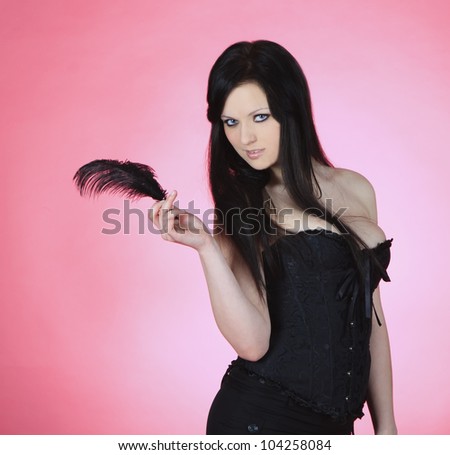 attractive young female with black feather over pink background
