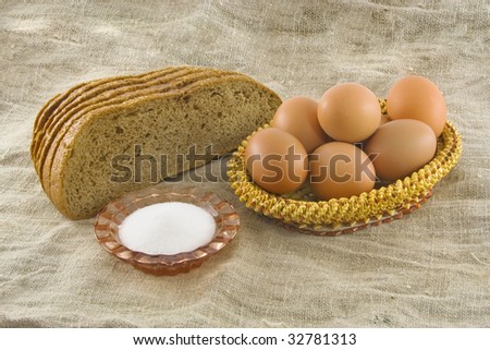 Still-life. Vegetarian products: rye bread from a flour of a rough grinding and the eggs lying in a wattled basket from straw on a sacking (a rough fabric)