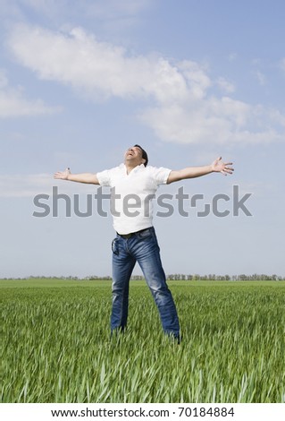 young man moves in a green field of grass to meet the sun