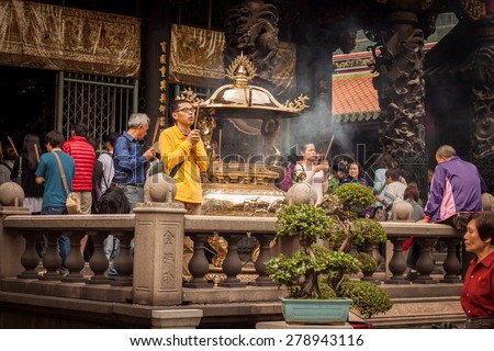 TAIPEI, TAIWAN - APRIL 23: a group of people pray in Longshan temple in Taipei, Taiwan on April 23th, 2015. Longshan Temple worships a mixture of Buddhist and Taoist deities.
