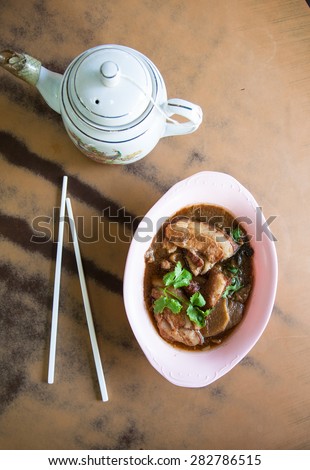 Chinese food  and chop sticks with teapot set on antique wood table. Stew pork in gravy sauce ,vintage tone.