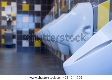 White porcelain urinals against a yellow and orange tiled wall